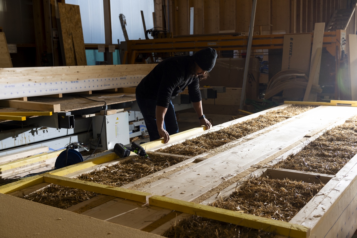 Préfabrication de l'ossature bois en atelier avec insertion de paille comme matériau isolant en décembre 2024